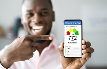 Man smiling holding a cell phone that shows a high credit score he increased with AI